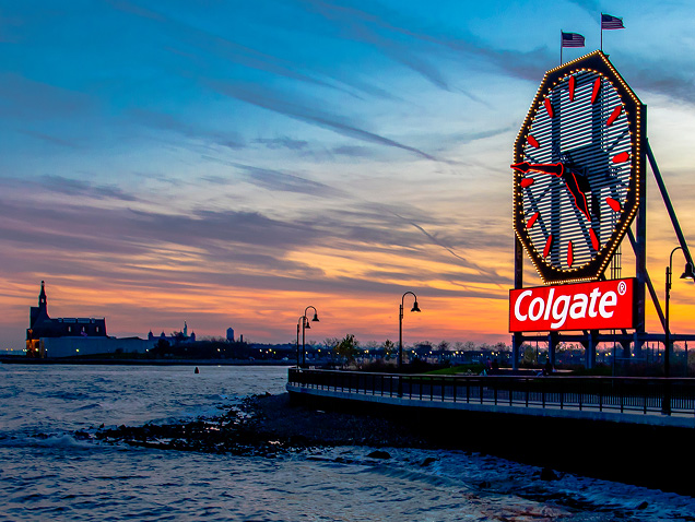 riva del mare, logo Colgate sullo sfondo sotto un grande orologio con le lancette rosse
