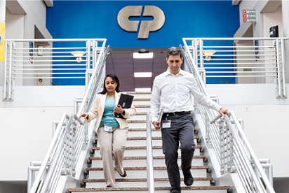 Dipendenti Colgate-Palmolive scendono una rampa di scale, con il logo Colgate-Palmolive alle loro spalle su una parete blu.